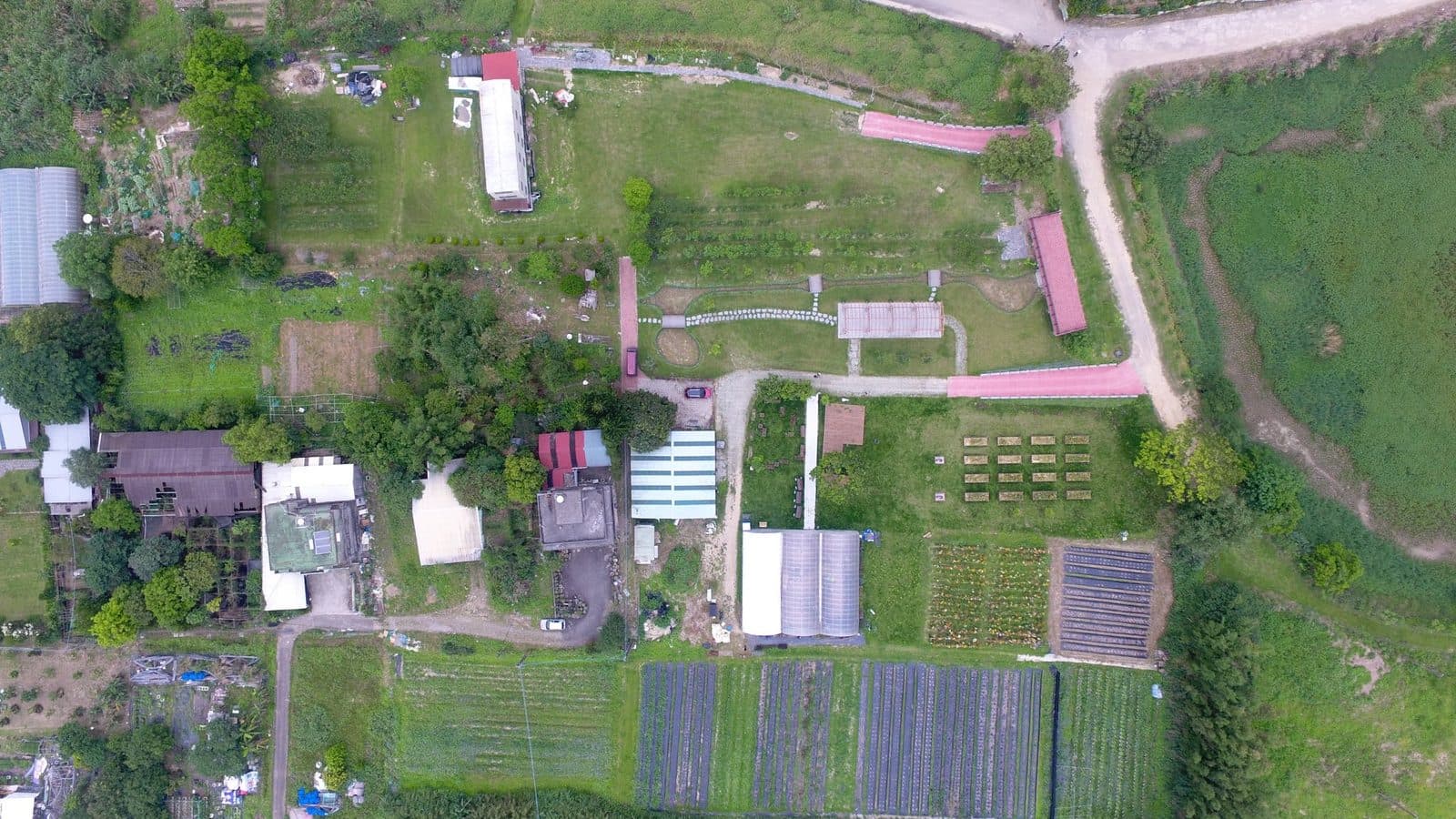 空拍一座社會性農場的全貌,溫室、菜畦、步道與樹林相連